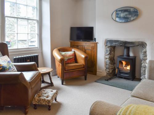 a living room with a fireplace and a chair at Campbell Cottage in Windermere