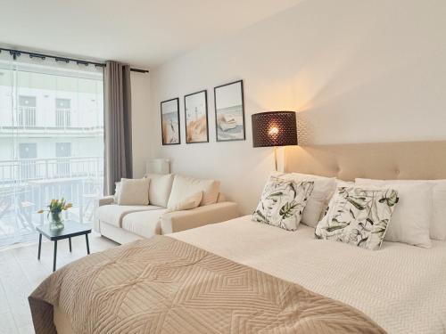 a white bedroom with a bed and a couch at Apartamenty Florina Q4Apartments in Łeba