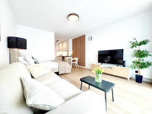 a white living room with a white couch and a table at Apartamenty Florina Q4Apartments in Łeba