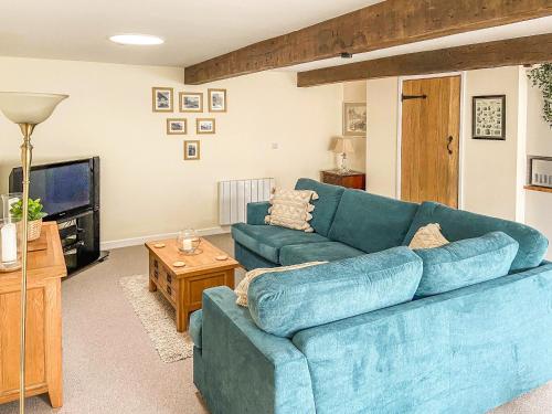 un soggiorno con un divano blu e una TV di The Old Dairy Annexe a Donyatt