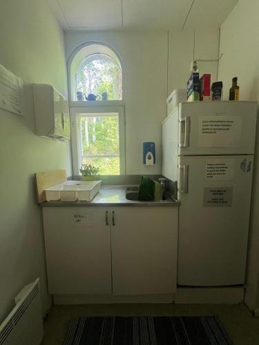 a kitchen with a white refrigerator and a window at Hostel Ukonlinna in Imatra