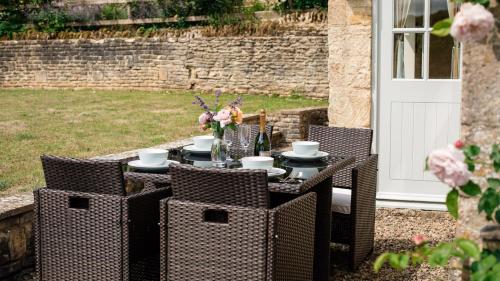 - une table extérieure avec des chaises, des tasses à café et des fleurs dans l'établissement Pickett Cottage, à Hampnett