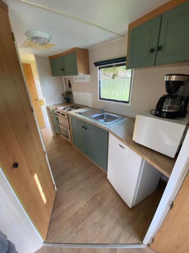 Elle comprend une petite cuisine avec des placards verts et un évier. dans l'établissement Camping de la Reuille, à Fléré-la-Rivière