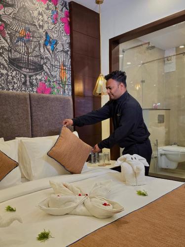 a man putting towels on a bed in a hotel room at Romeo Lane Mussoorie - The Courtyard House in Mussoorie