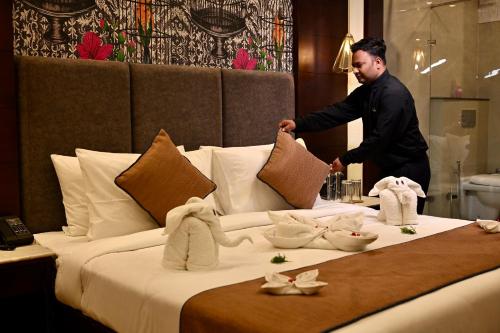 a man is making a bed in a hotel room at Romeo Lane Mussoorie - The Courtyard House in Mussoorie