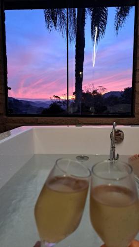 two glasses of wine in a bath tub with a sunset at Refúgio na Serra com Pôr do Sol in Feliz