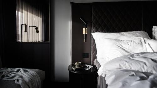 a bedroom with a bed with a black headboard and white sheets at At Six in Stockholm