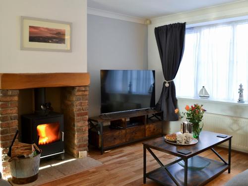 a living room with a television and a fireplace at April Cottage in Sewerby