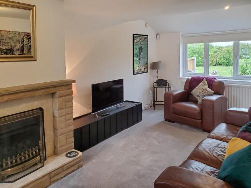 a living room with a fireplace and a television at Windmill Cottage in Little Eaton