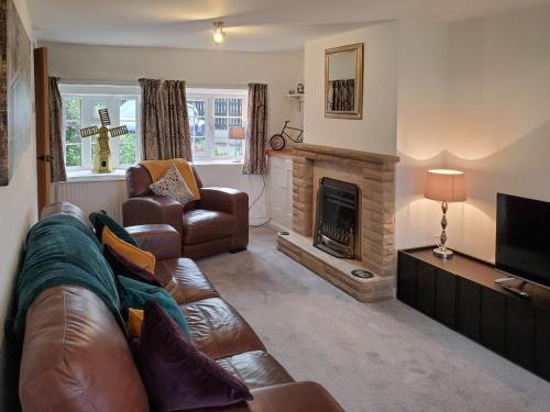 ein Wohnzimmer mit Couch und Kamin in der Unterkunft Windmill Cottage in Little Eaton