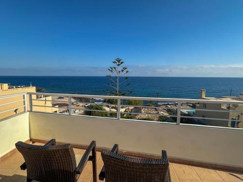 two chairs sitting on a balcony overlooking the ocean at Aegean Blue Seafront Apartment in Sissi