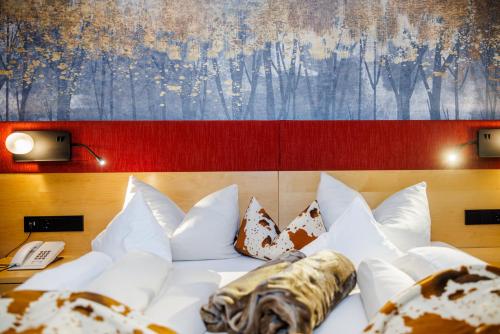 a bed with white pillows and a painting on the wall at Hotel Landhaus Carla in Mayrhofen