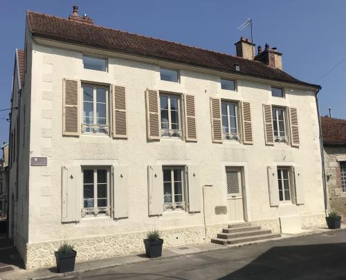 a white building with windows and shutters on it at La Maison d'Hyppolite in Châtillon-sur-Seine