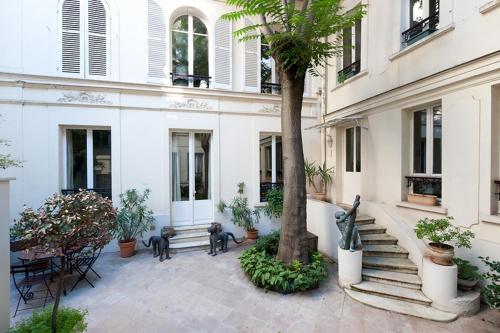 une cour avec un arbre et des bancs et un bâtiment dans l'établissement Hotel des Bains, à Paris