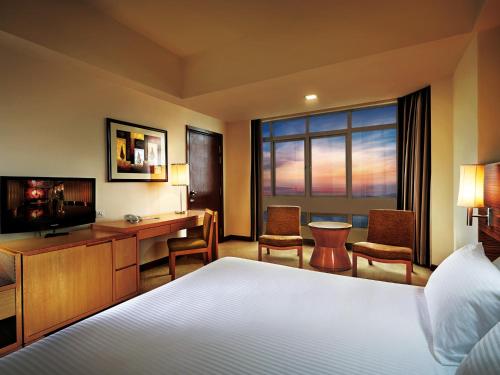 Habitación de hotel con cama, escritorio y TV. en Resorts World Genting - Resort Hotel, en Genting Highlands