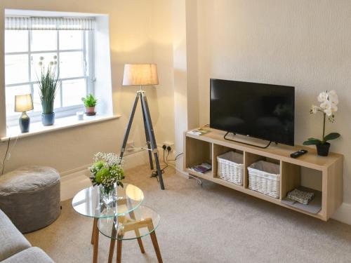 a living room with a flat screen tv on a stand at The Nest in Helmsley