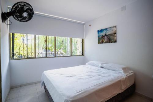 a white bedroom with a bed and a window at Casa Fonla in Estación El Salto