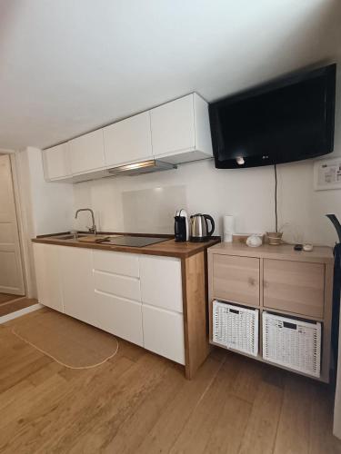 a kitchen with white cabinets and a flat screen tv at Apartments Nicole in Porto Rotondo