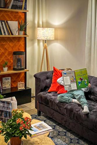 a person laying on a couch with a laptop at The Originals Boutique, Hôtel Le Londres, Saumur in Saumur
