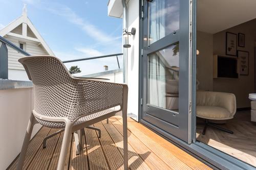 a chair on the balcony of a house at Boutique Hotel Helder I Kloeg Collection in Renesse
