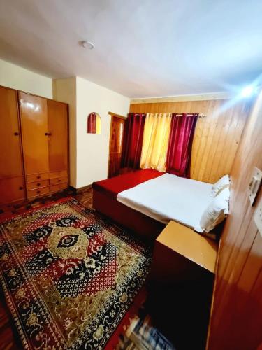 a bedroom with a bed and a rug at Snow land cottage in Manāli