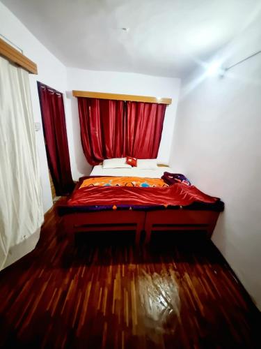 a bedroom with a bed with a red curtain at Snow land cottage in Manāli