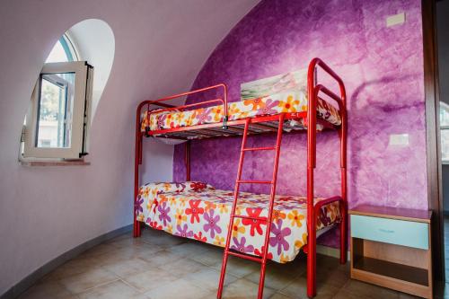 a red bunk bed in a room with a purple wall at Camping & Village Rais Gerbi in Pollina