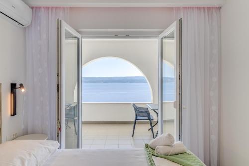 a bedroom with a view of the ocean at DeLuxe Seaview Apartment KENNEDY I in Mimice