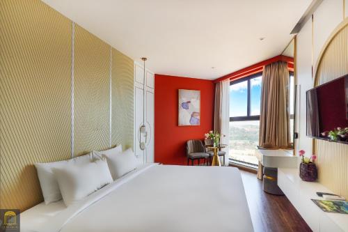 a bedroom with a large white bed and a red wall at Apec Mandala de Suite Mũi Né in Mui Ne