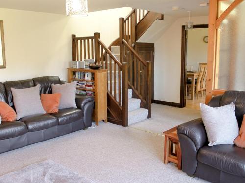 ein Wohnzimmer mit 2 Ledersofas und einer Treppe in der Unterkunft Swallow Cottage in Shanklin