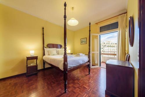 a bedroom with a four poster bed and a balcony at Casa Branca Apartment by Mth in Funchal