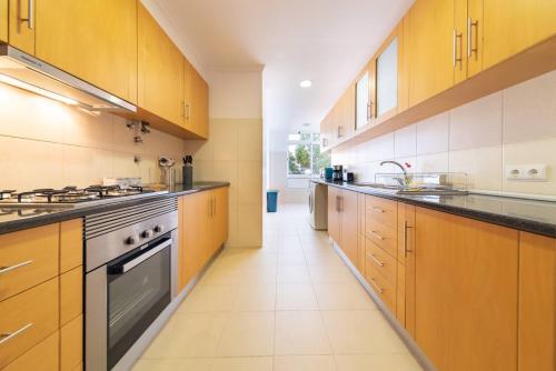 a large kitchen with wooden cabinets and a stove at Casa Branca Apartment by Mth in Funchal