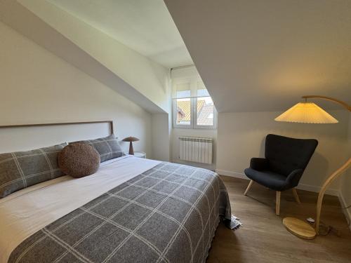a bedroom with a bed and a chair and a lamp at Doña Carmen en el corazón Cangas Onís VUT-6783-AS in Cangas de Onís