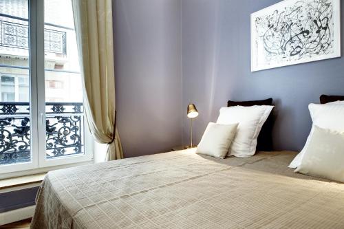 une chambre avec un lit avec des oreillers blancs et une fenêtre dans l'établissement Paris Marais Design residence, à Paris