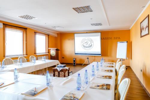 a meeting room with white tables and chairs and a screen at Spa Hotel Gloria in Przemyśl