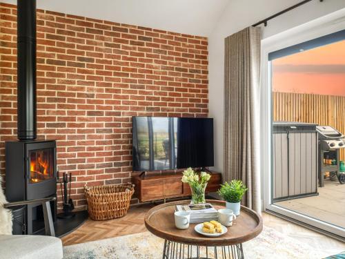 ein Wohnzimmer mit einer Ziegelwand und einem Kamin in der Unterkunft Uk47693 - Piglet Cottage in Wimbish