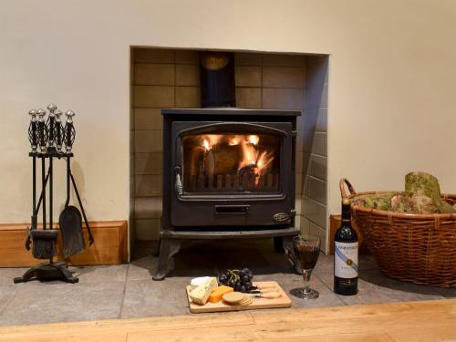 a stove in a living room with a fireplace at Inn Cottage in Glendevon