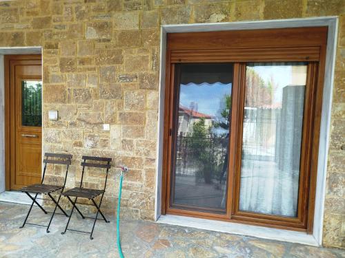 two chairs sitting next to a window with a hose at THANground floor in Nea Kalikratia