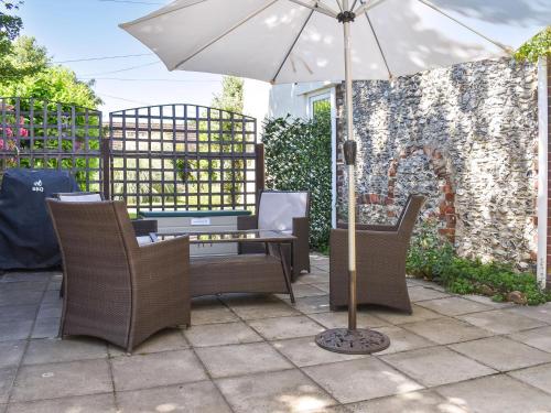 Sunbury Cottage في Clanfield: طاولة وكراسي مع مظلة على الفناء