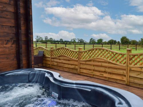bañera de hidromasaje en una terraza con una valla de madera en Pheasant Lodge - Uk33402, en Hungerton