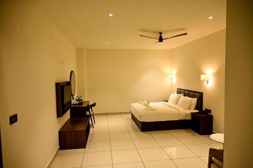 a hotel room with a bed and a television at Hotel S S International Coorg in Suntikoppa
