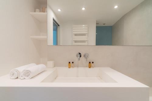 une salle de bain blanche avec un lavabo et un miroir dans l'établissement Veeve - The Ecologist, à Paris