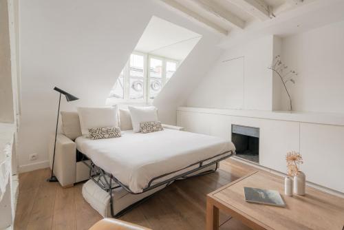 une chambre blanche avec un lit et une cheminée dans l'établissement Veeve - The Ecologist, à Paris