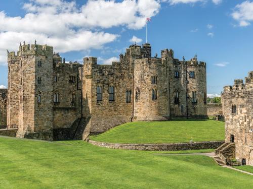 an old castle with a green lawn in front of it at Spring Tides in Beadnell