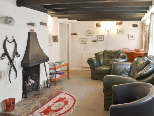 a living room with two chairs and a fireplace at Mill Cottage in Buckfastleigh