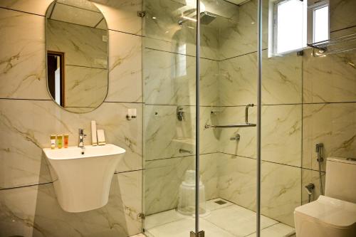 a bathroom with a shower with a sink and a mirror at Hotel S S International Coorg in Suntikoppa