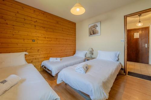 - 3 lits dans une chambre dotée d'un mur en bois dans l'établissement Serac 2 - Snow and Trek, à Morzine