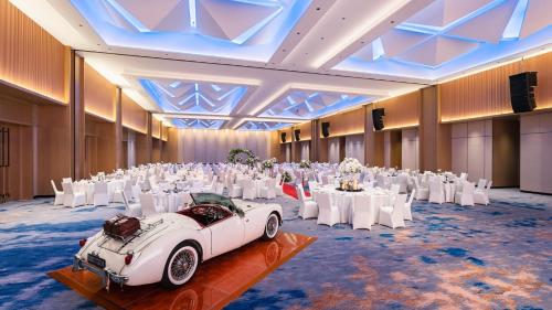 a room with white tables and a white car in it at Holiday Inn & Suites Penang Prai by IHG in Bukit Mertajam