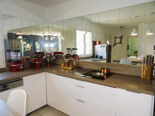 une grande cuisine avec des placards blancs et un grand miroir dans l'établissement Évasion au bord de mer, Appartement avec piscine, au Barcarès