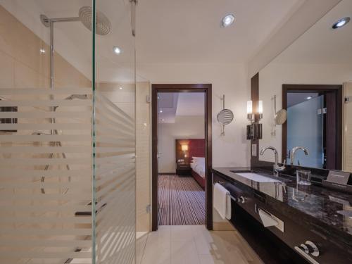 a bathroom with a glass shower and a sink at Steigenberger Graf Zeppelin in Stuttgart